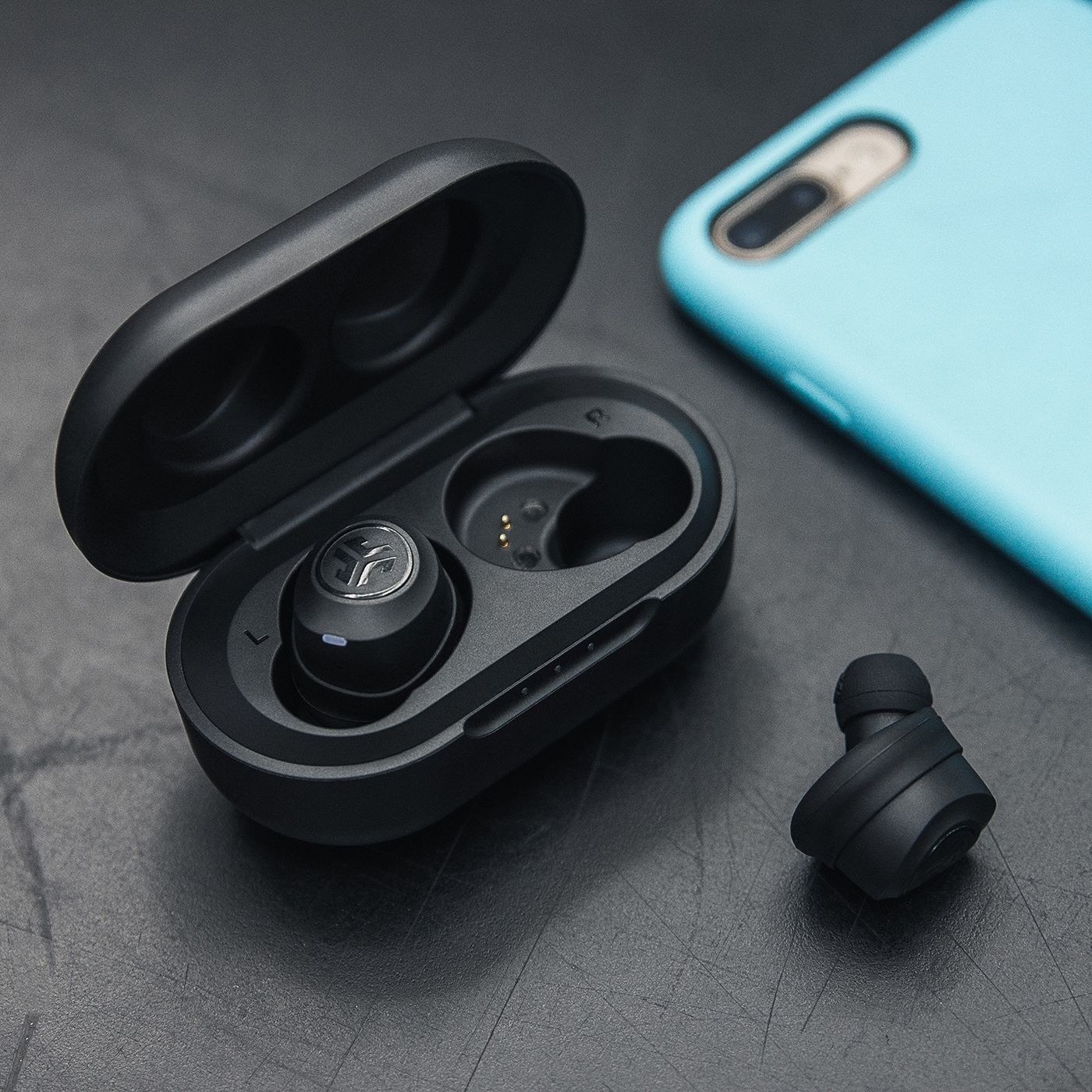 The wireless earbuds in their charging case next to a smart phone