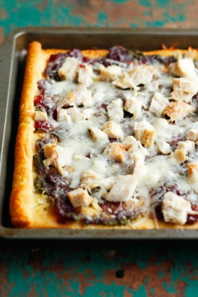 A crescent roll pizza topped with cranberry sauce and diced turkey.