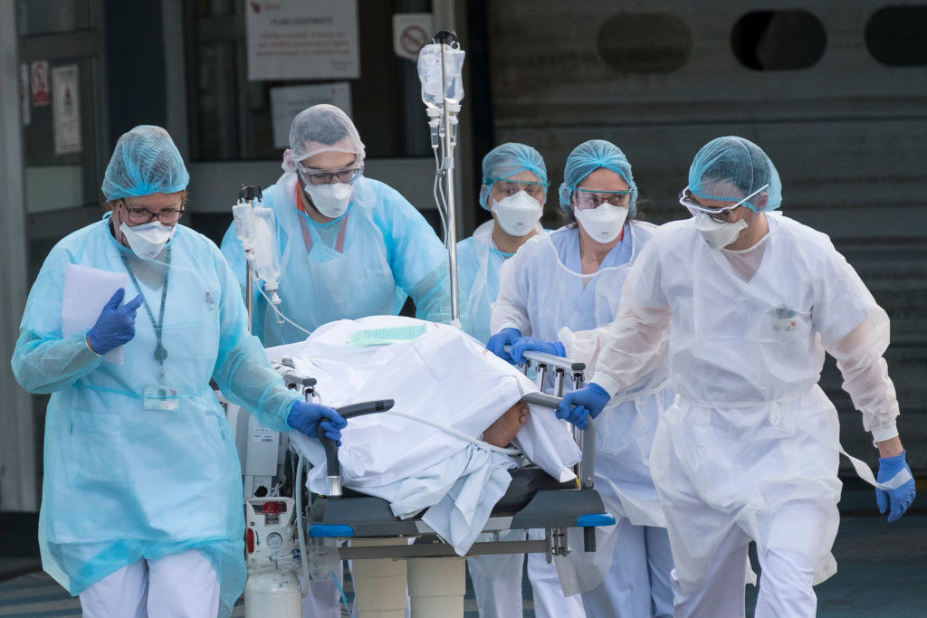 Several medical professionals wheeling a patient on a gurney