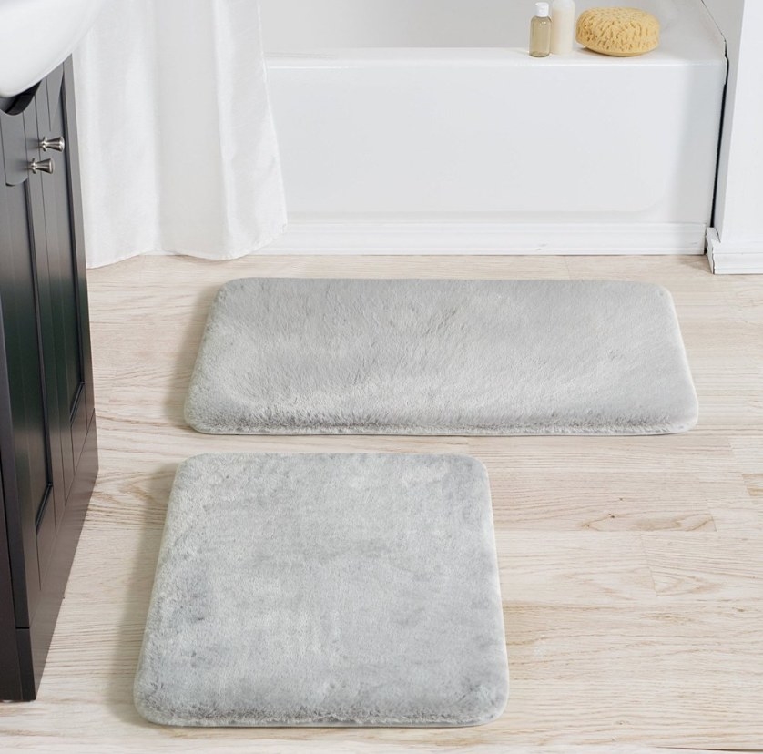 Two silver faux fur bath mats, one small square, one larger rectangle
