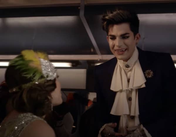 Adam, dressed as a vampire, talks to Aria