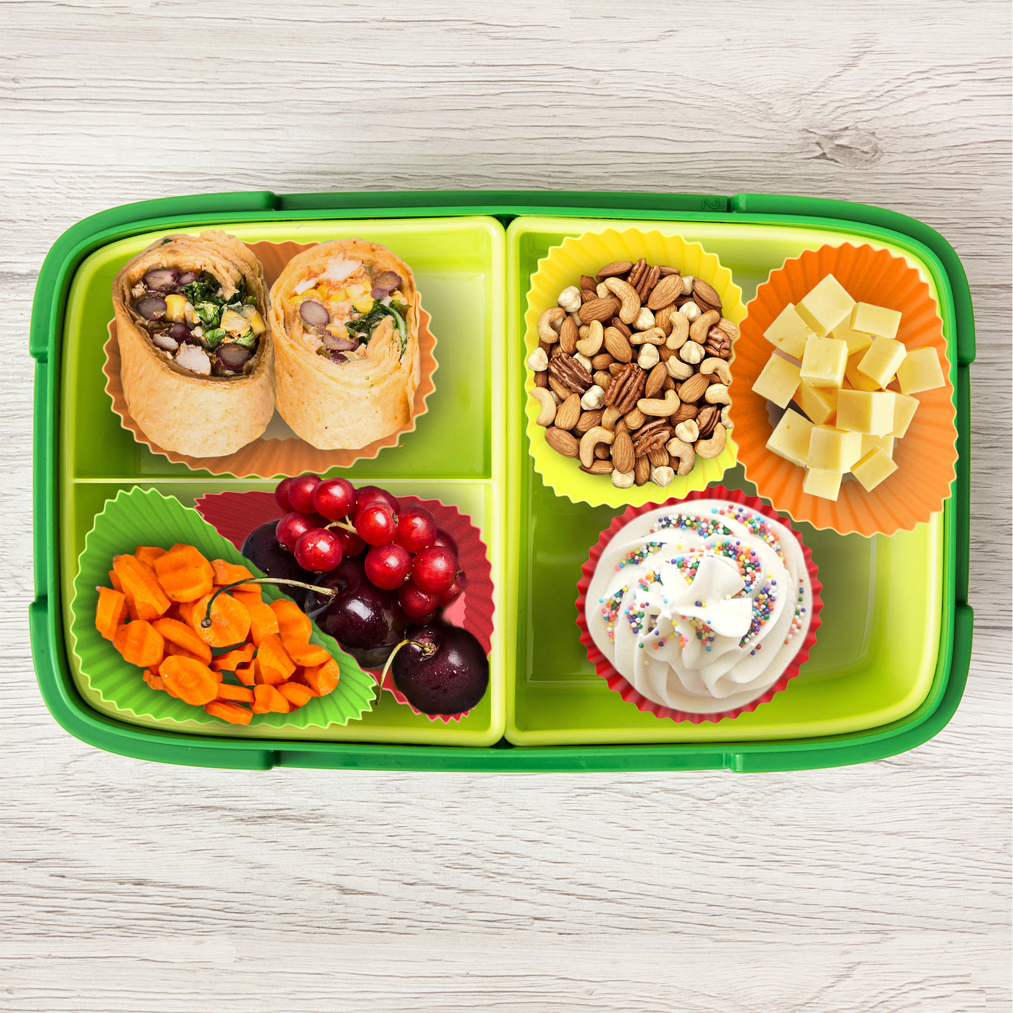 Colorful silicone liners dividing food up in a yellow and green lunchbox