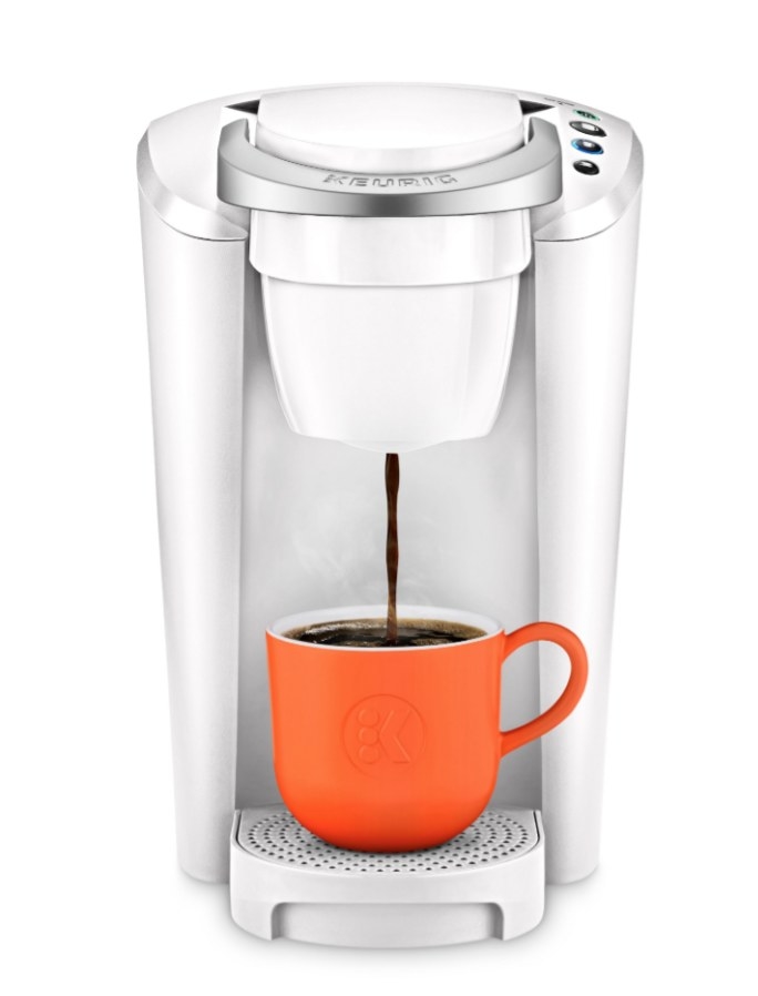 White Keurig filling orange mug with coffee