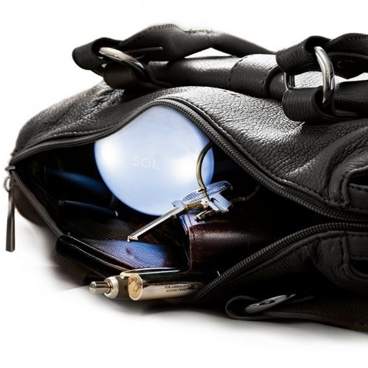 A black purse unzipped so the light inside is visible 
