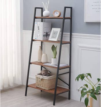 Black and wood ladder shelf with books, trinkets, and storage baskets