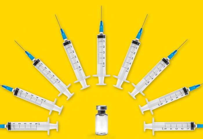 Several syringes arc over a vaccine vial. 