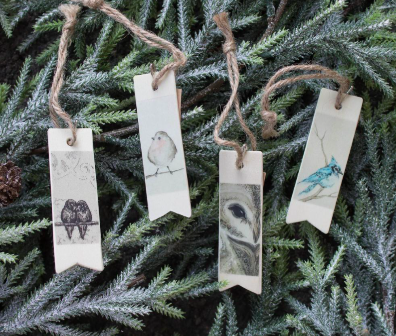 A series of wildlife-themed wooden gift tags on pine boughs