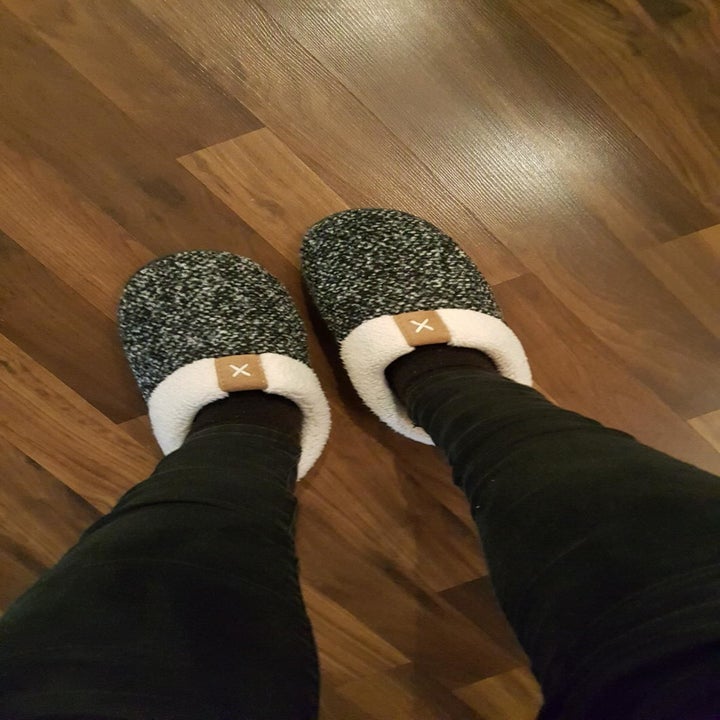Reviewer wears gray anti-slip slippers while walking on hardwood floors at home