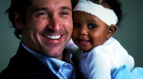 Derek holding Zola (as a baby) and smiling.