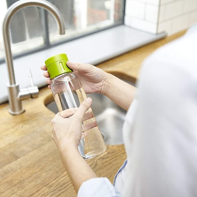 Clear bottle with a green lid that has the water tracker on it.