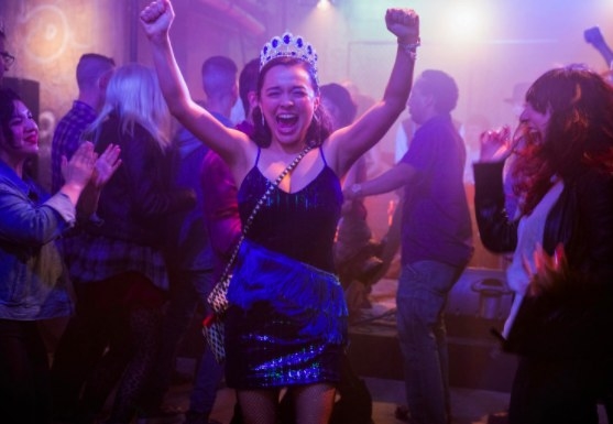 Lily wears a crown and triumphantly dance sin a crowd of people