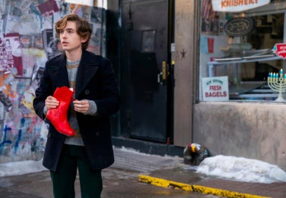 Dash stands in the street holding a red cowboy boot