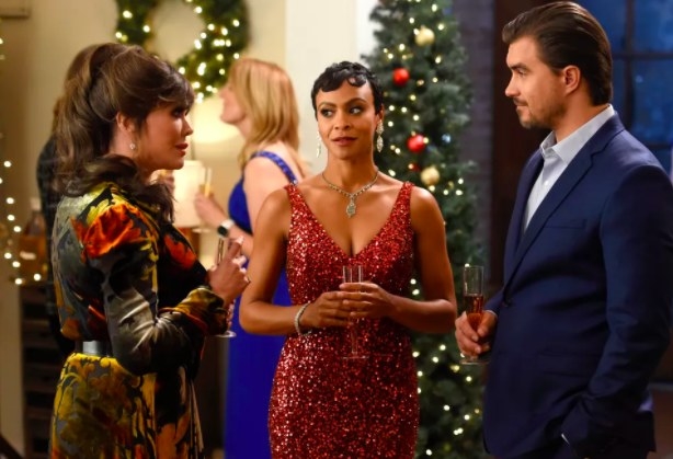 Carly Hughes, Rob Mayes and Marie Osmond stand together in a room decorated for Christmas, wearing formal attire