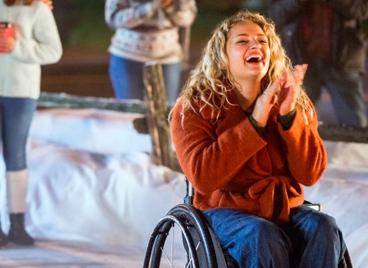  Ali Stroker, a wheelchair user, laughs and claps in a snowy setting
