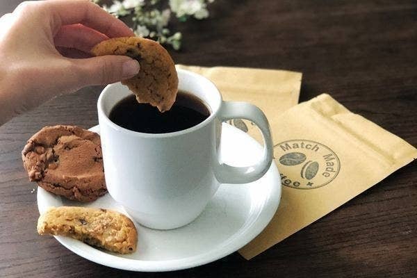 A person dipping a cookie into a cup of coffee