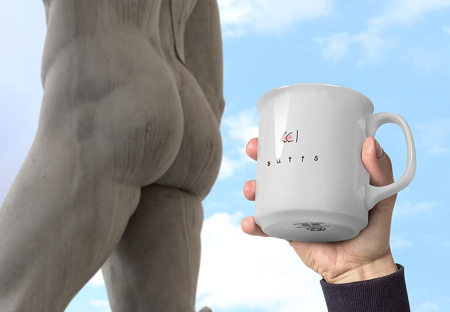 A person holding the mug next to a statue