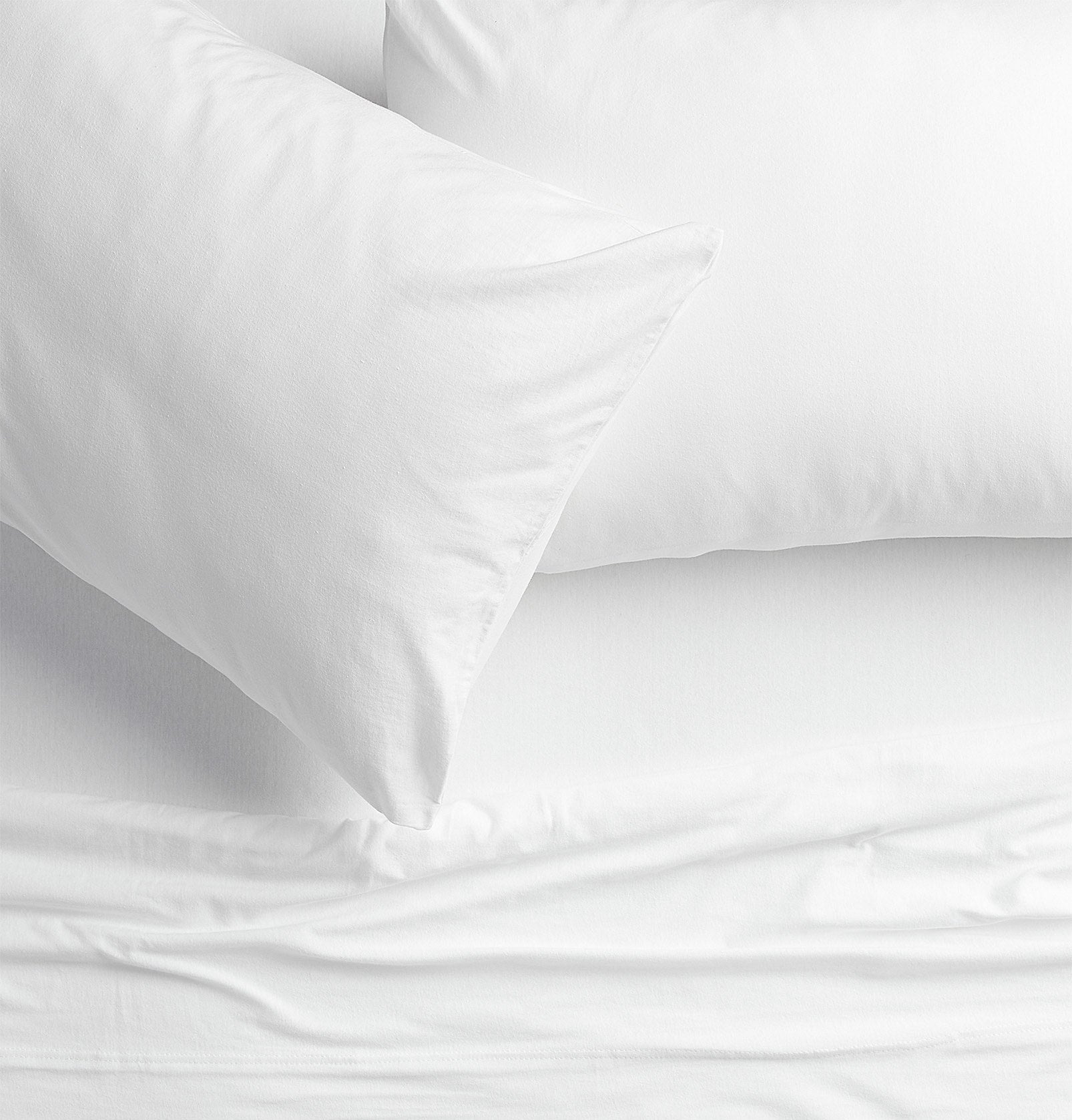 Two pillows on a bed with a top sheet