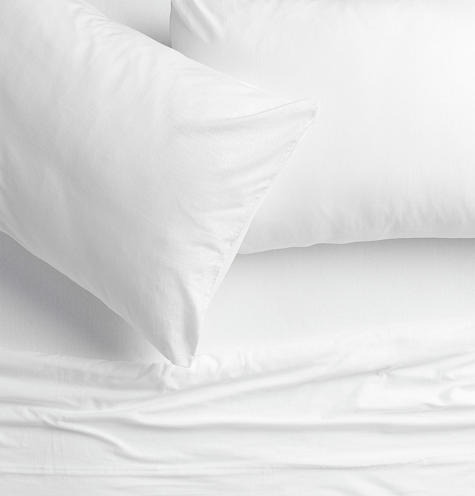 Two pillows on a bed with a top sheet