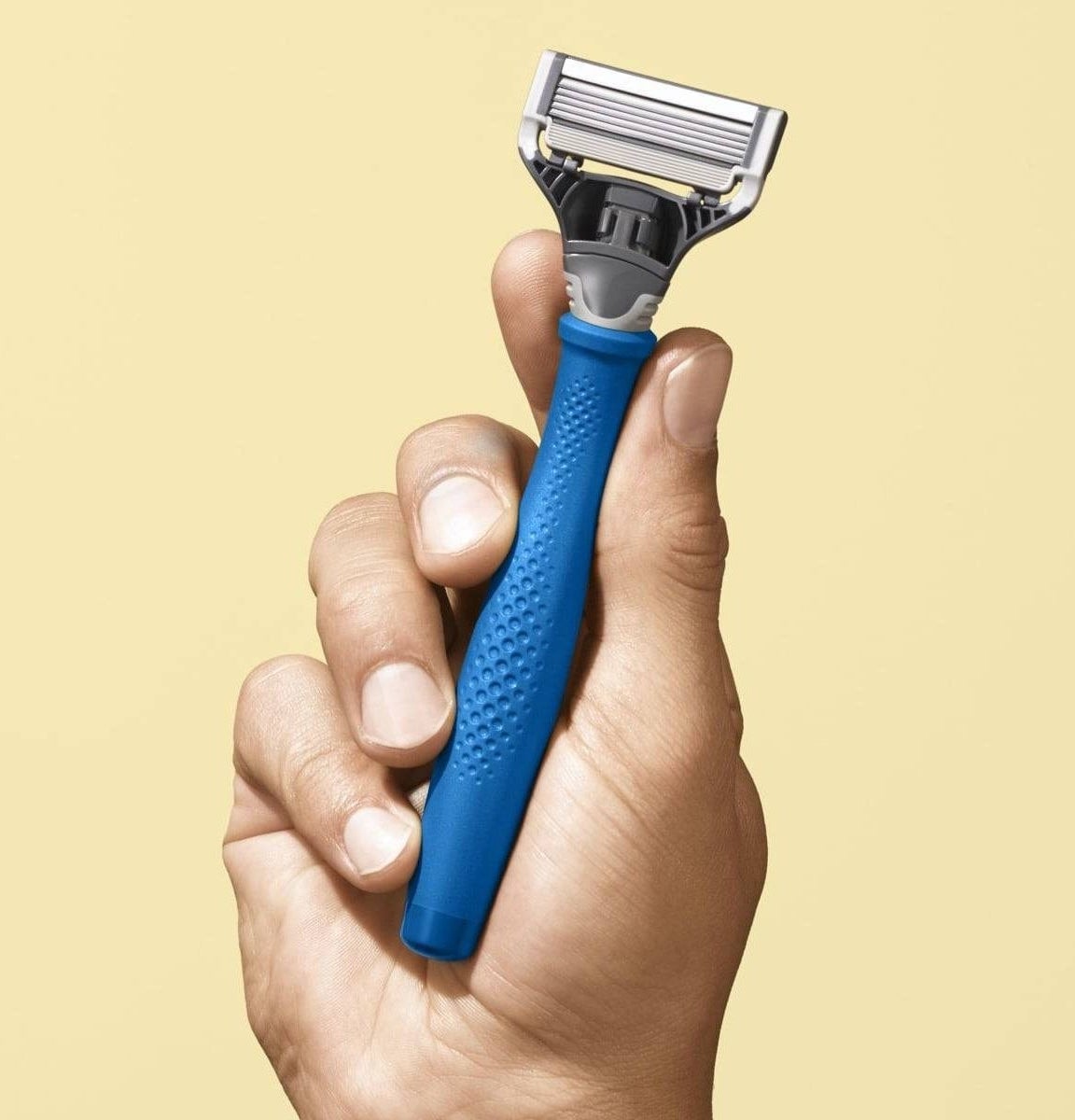 The razor being held to show its five blades and size