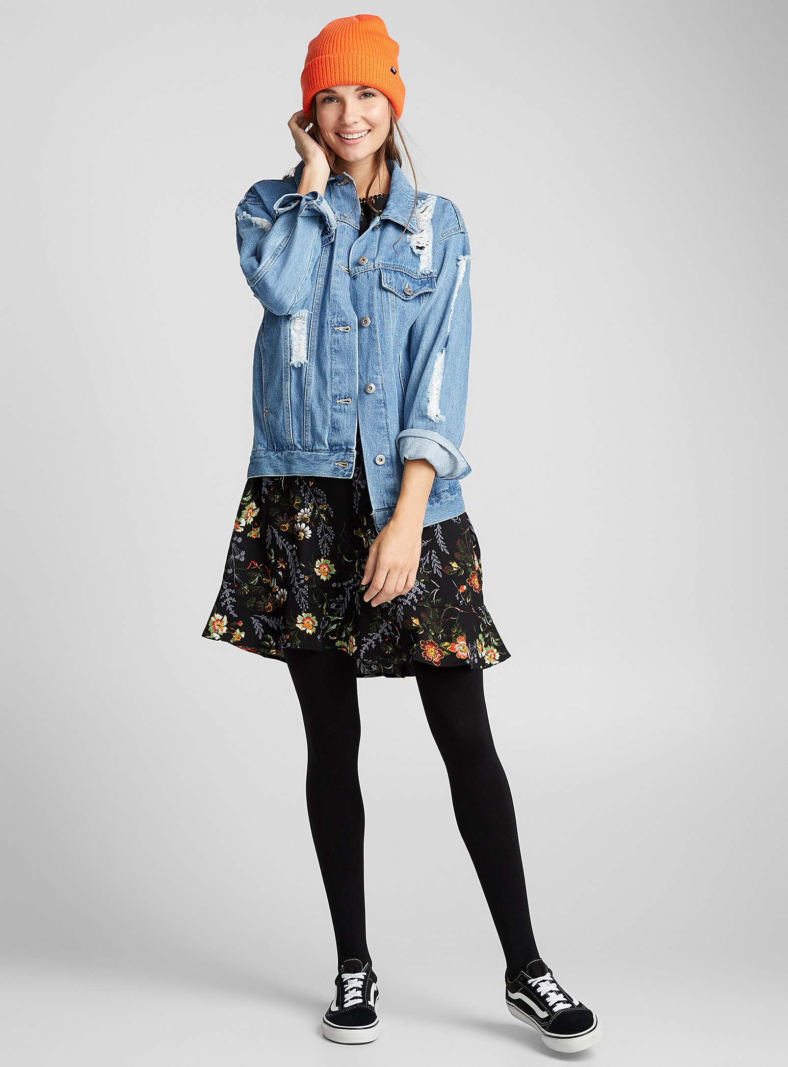 A person wearing thick tights with a dress and denim jacket