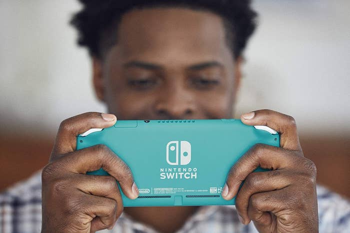 A man happily playing his Nintendo Switch Lite
