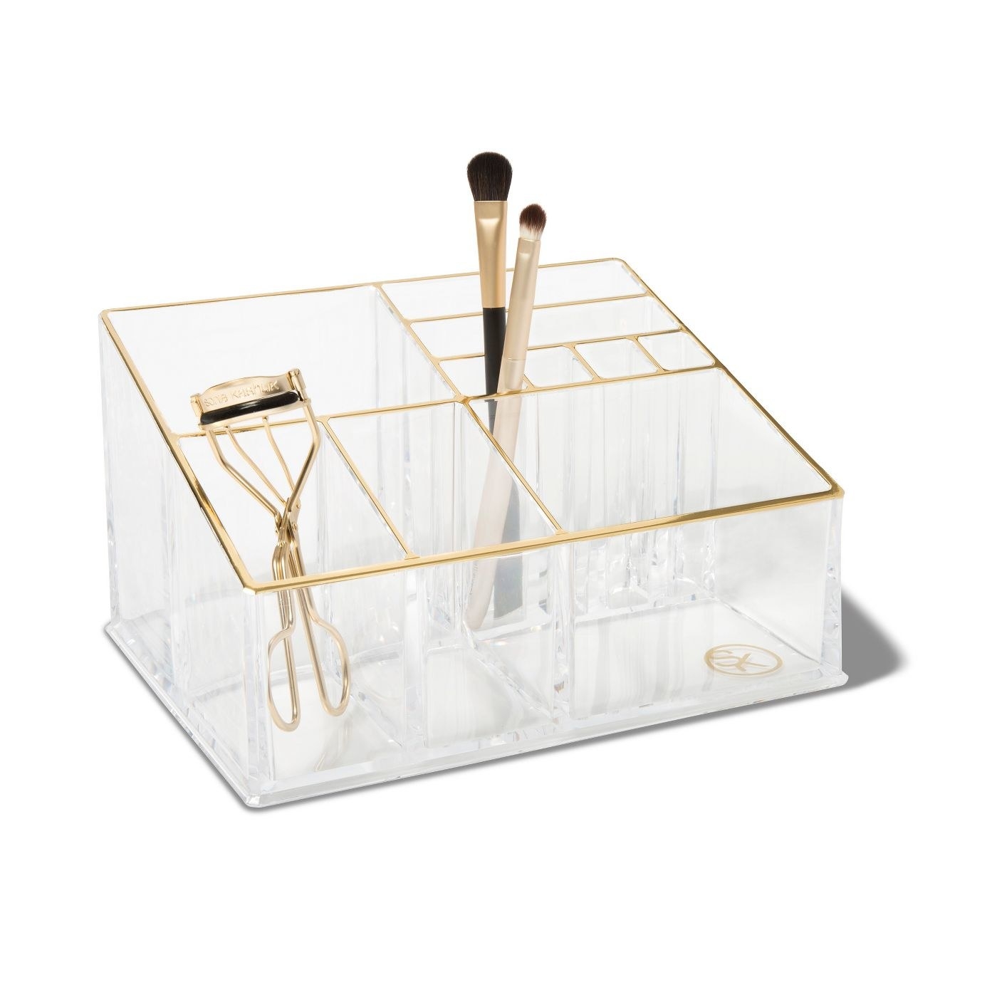 The makeup organizer holding brushes and a mascara curler to show the size of its compartments