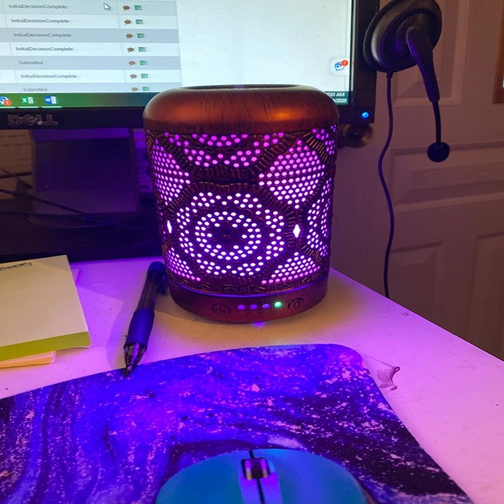 Reviewer uses copper engraved essential oil diffuser on their desk next to a computer monitor and swirly mouse pad