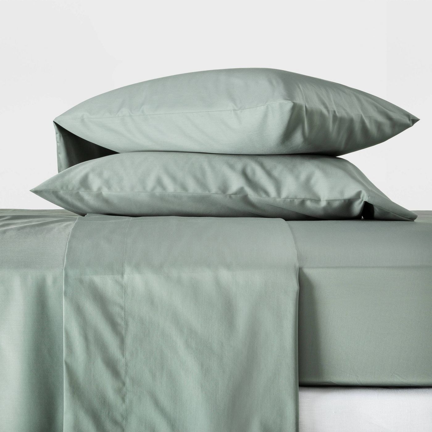 The sheets spread out over a bed in a soft green color