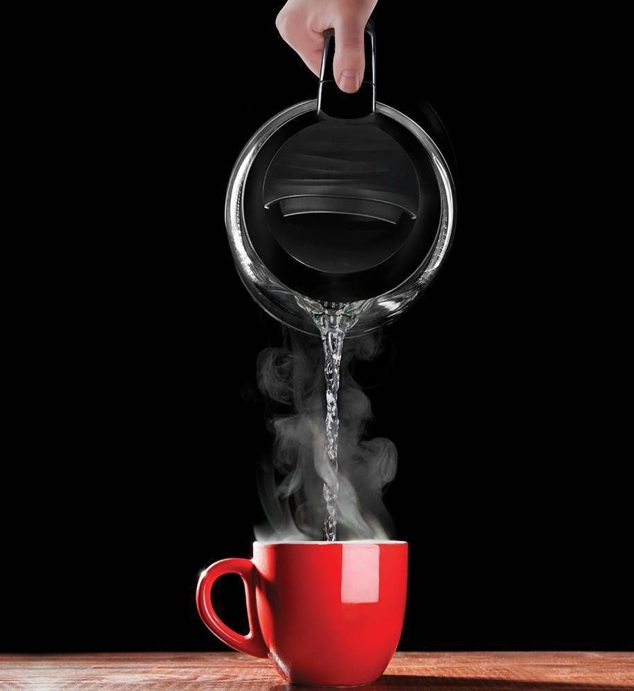 The electric kettle&#x27;s hot water contents being poured into a cup