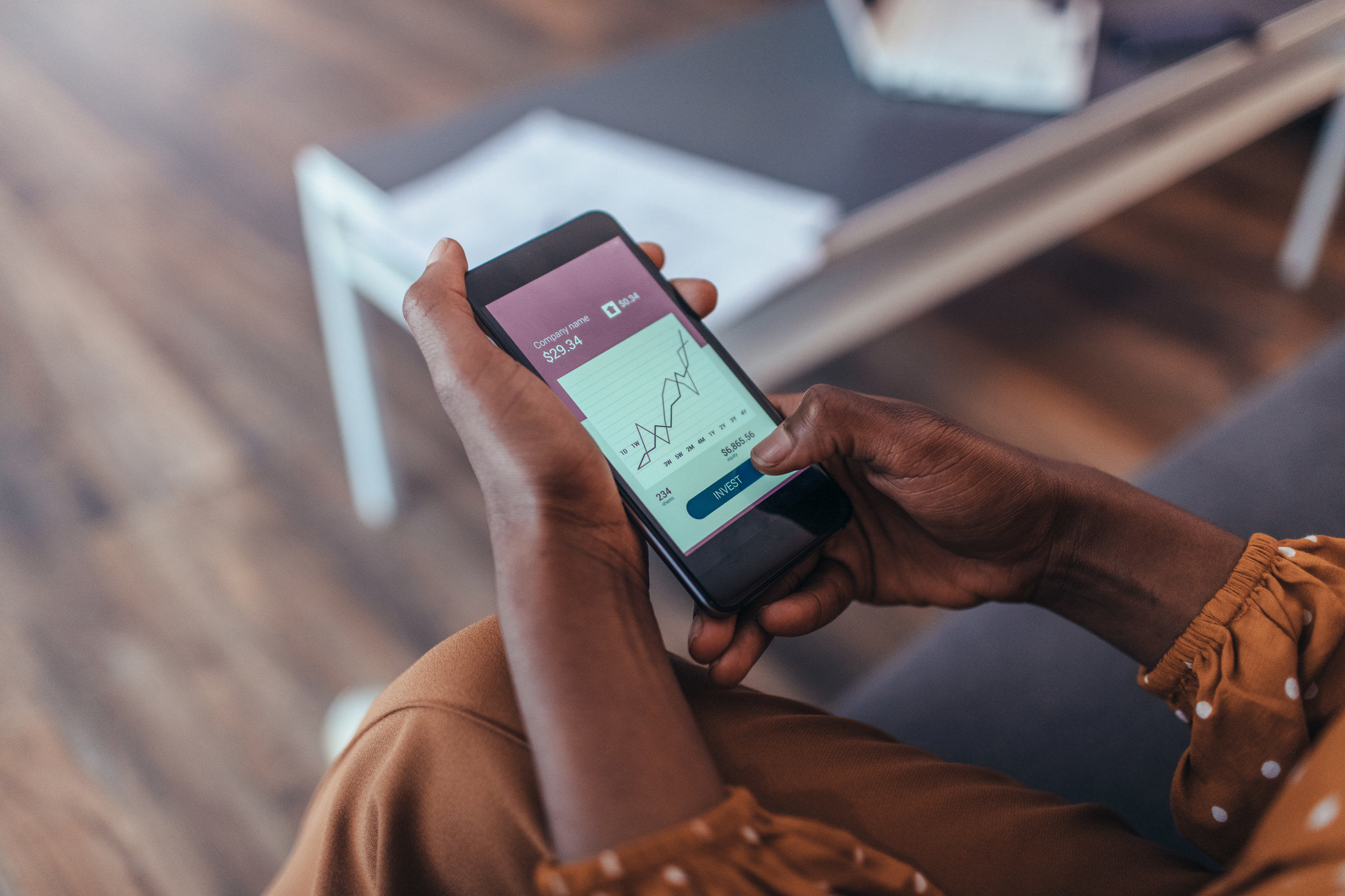 A model holding a phone with a stock chart on it