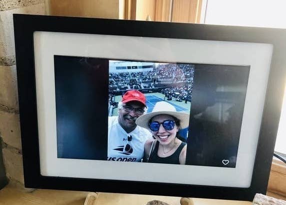 The frame with a white and black frame around the digital screen with a picture of the reviewer and their father at a tennis match