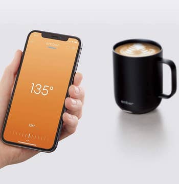 Model holding smartphone in front of Ember mug with the accompanying app