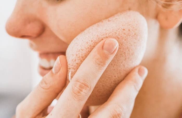 A person using the konjac sponge on their face