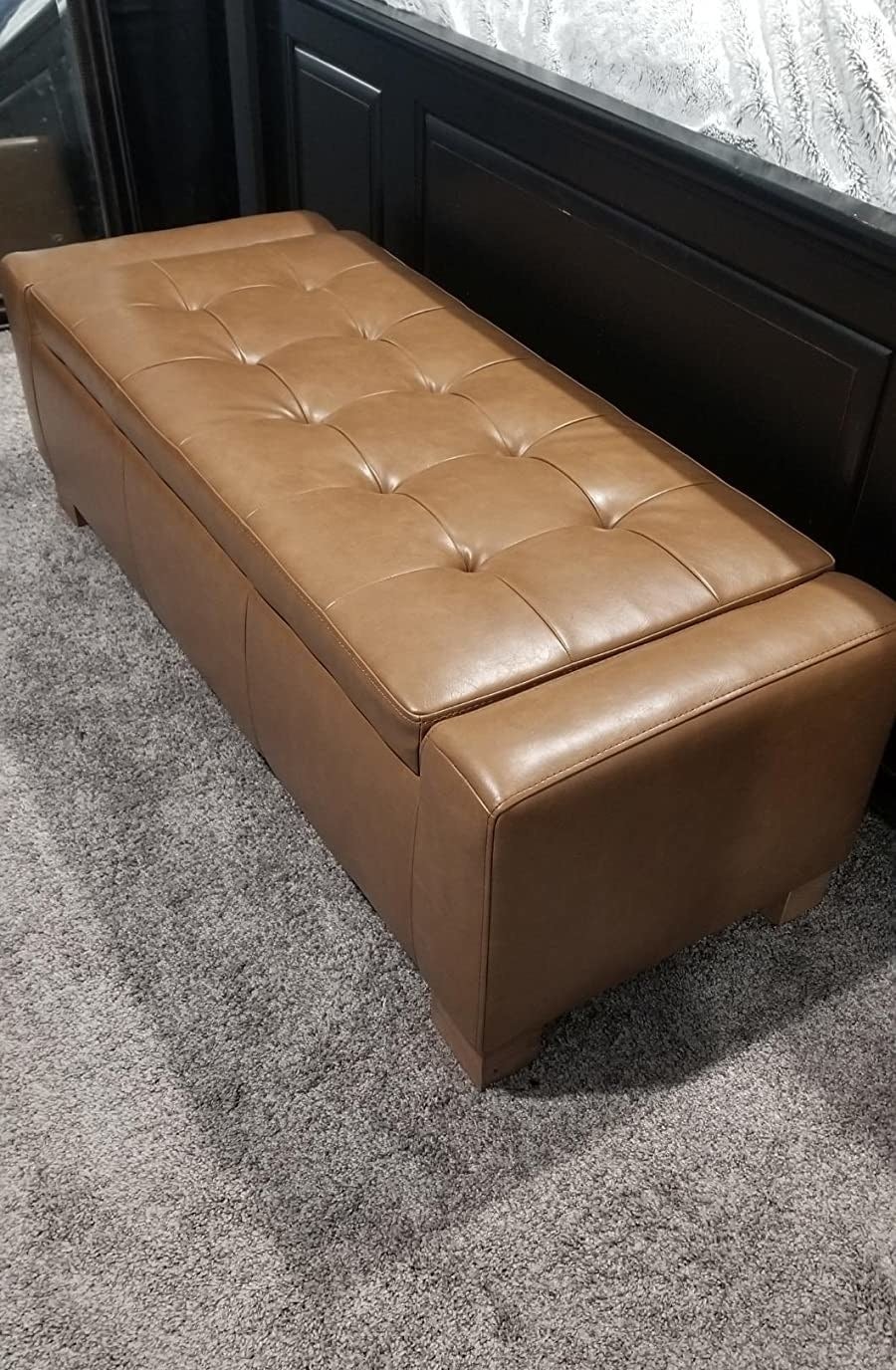 reviewer image of the retro brown leather chita storage bench in a bedroom