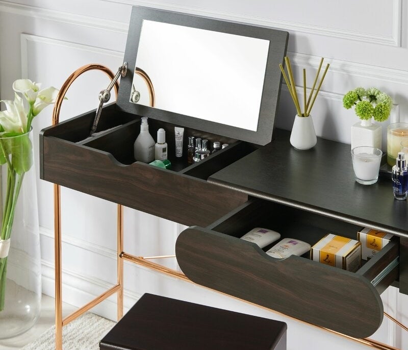 The wooden desk with arched metal legs, a drawer, and a flip-top mirror