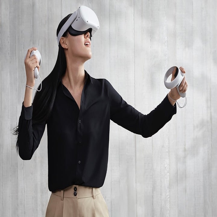 A model wearing the Oculus Quest 2 headset and holding a controller in each hand 