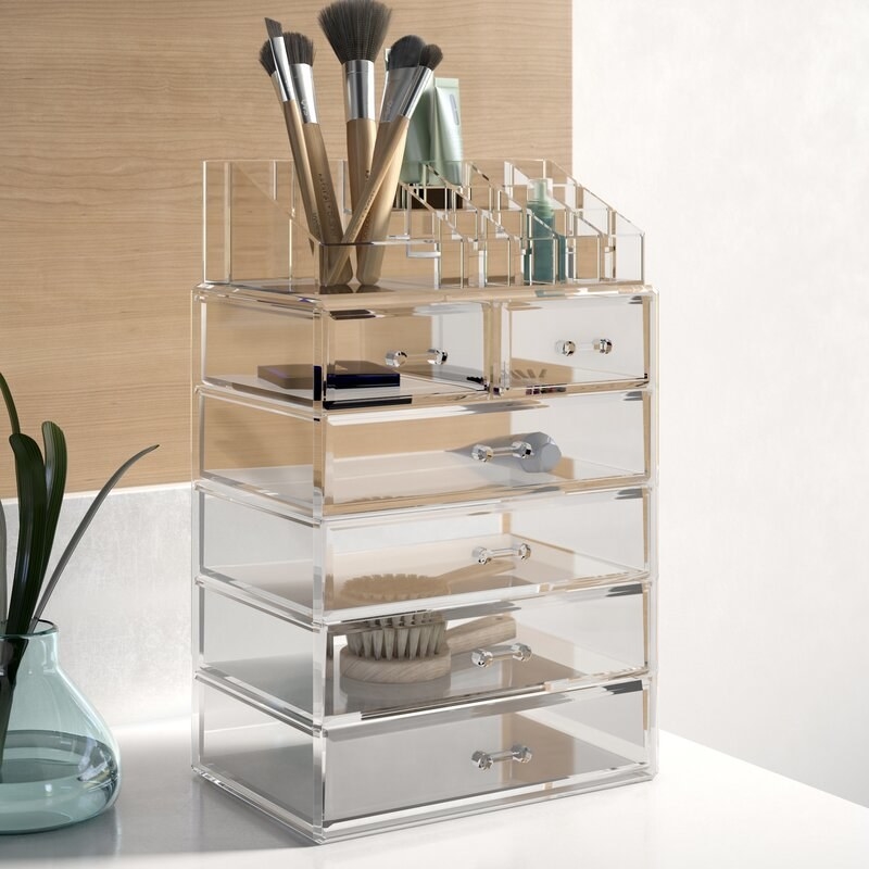 An acrylic set of drawer with four wide drawers, two skinny drawers, and a slanted organizer on top