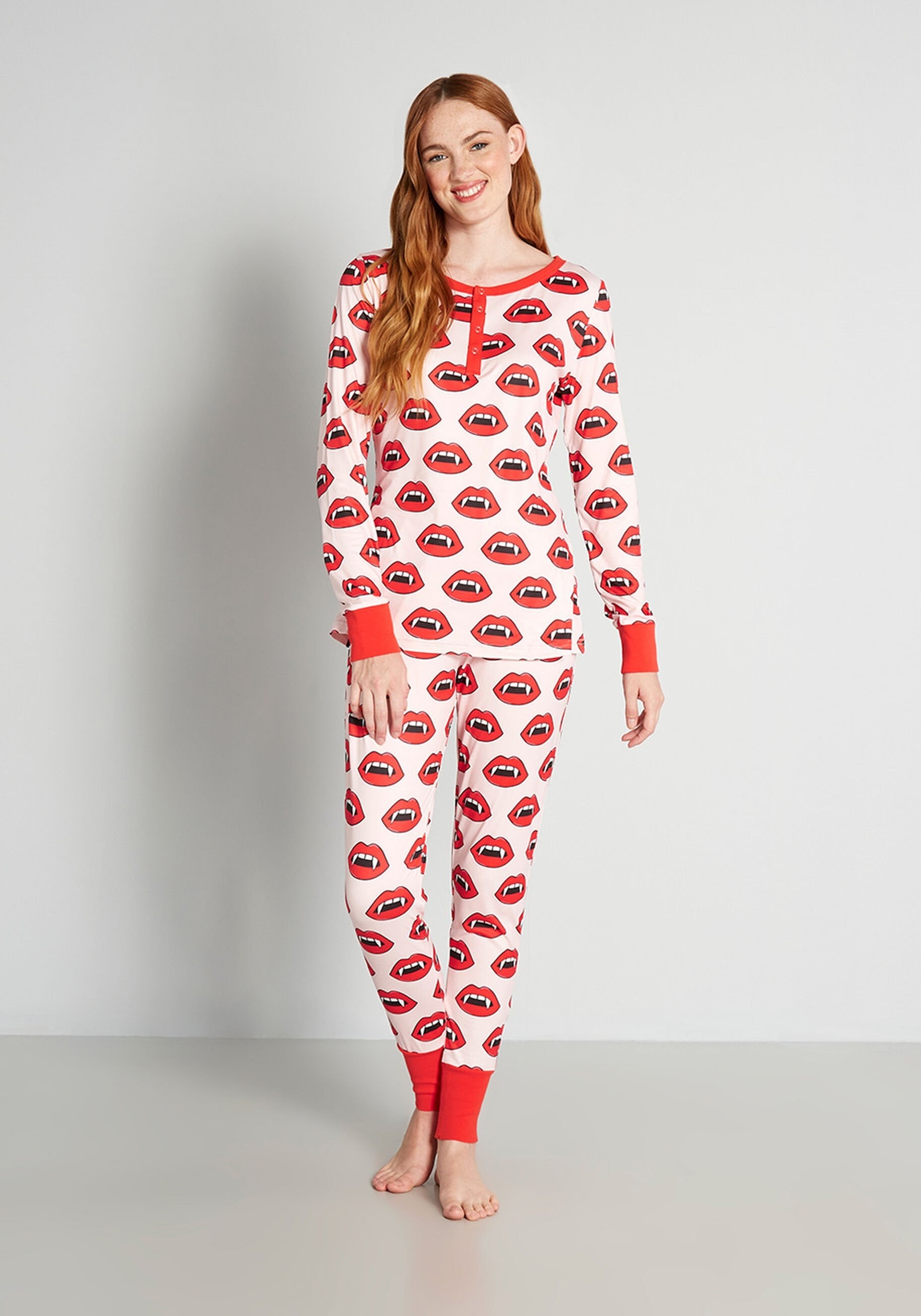 a model wearing long sleeve pink pajamas with red fang lips on it
