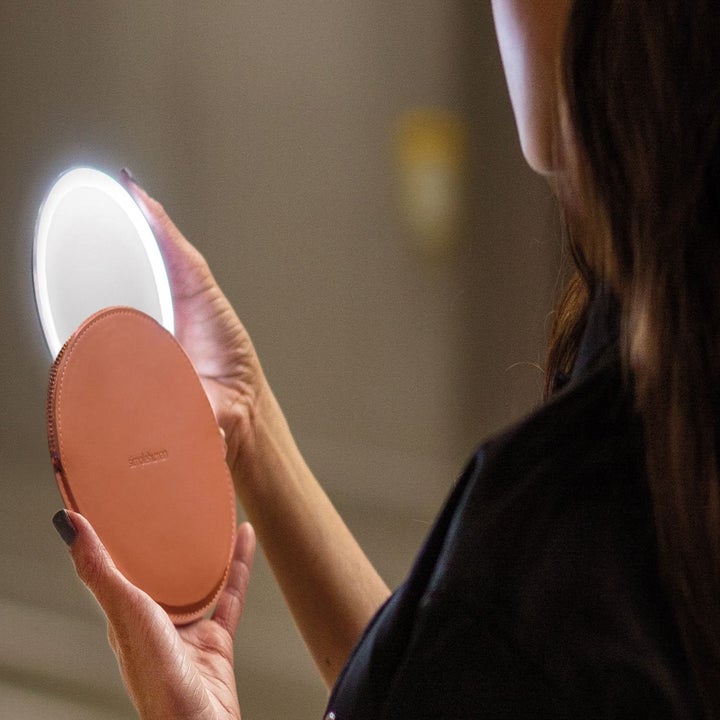A model pulling the illuminated compact out of the included pouch 