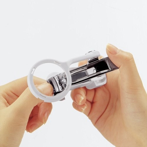 A person cutting their nails with clippers that have an attached magnifying glass
