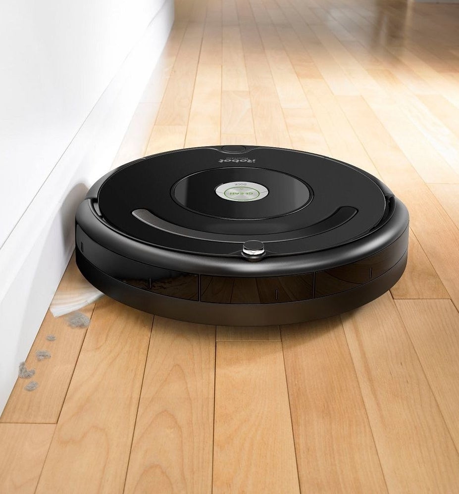 The Roomba sweeping up dust alongside a wall