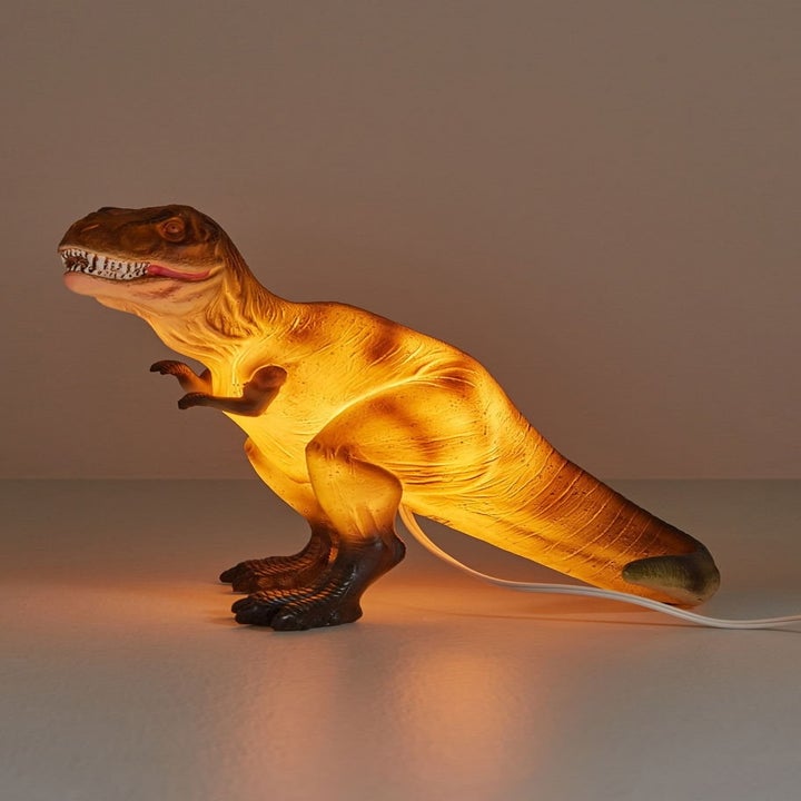 Yellow and red T-Rex shaped lamp on table
