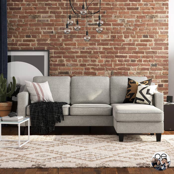 A grey sectional sofa in front of a brick wall