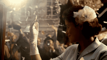 GIF of a young Queen Elizabeth waving a gloved hand to adoring crowds in the street