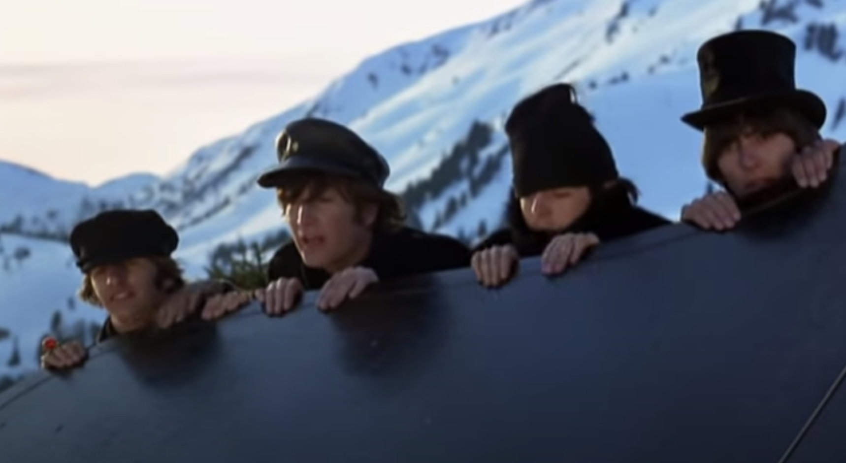 The four Beatles look over a ledge in the snowy alps
