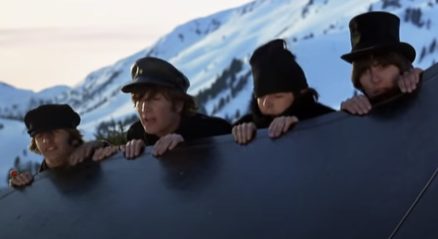 The four Beatles look over a ledge in the snowy alps