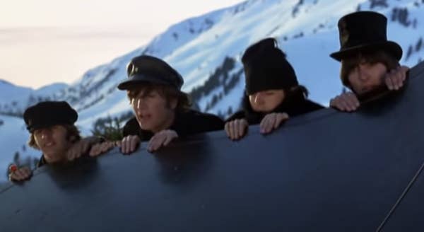 The four Beatles look over a ledge in the snowy alps