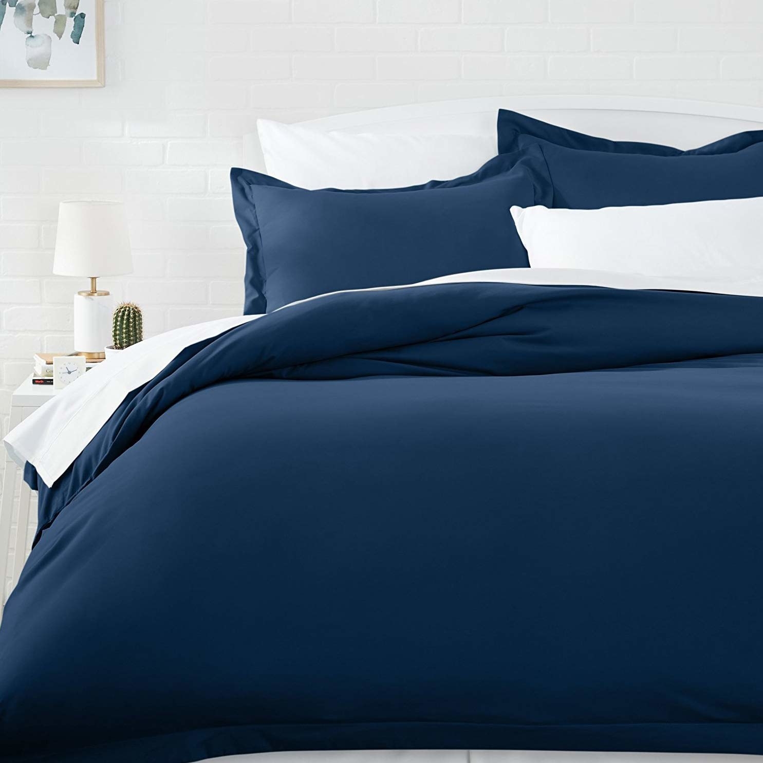 A blue duvet cover on a bed beside a bedside table 