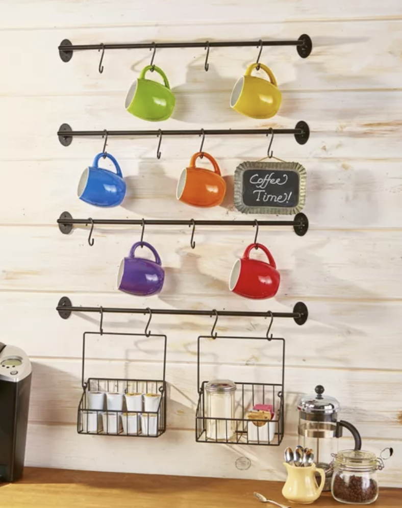 Four metal bars installed on a wall, each with four hooks to hold mugs, plus two small hanging baskets to hold spices
