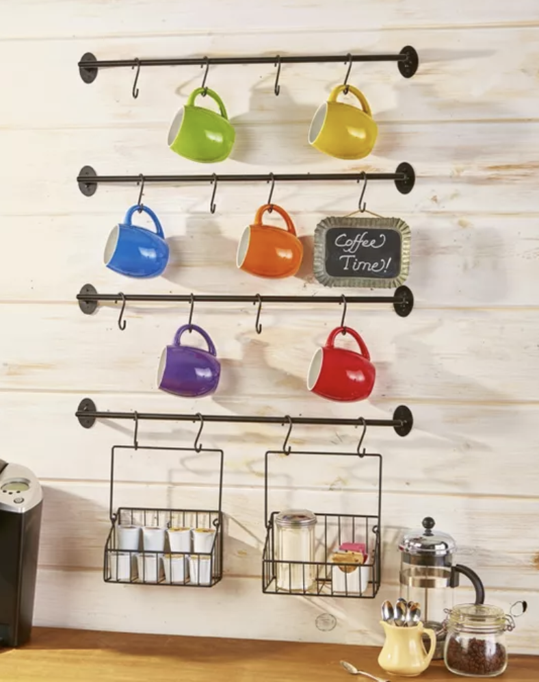 Four metal bars installed on a wall, each with four hooks to hold mugs, plus two small hanging baskets to hold spices 